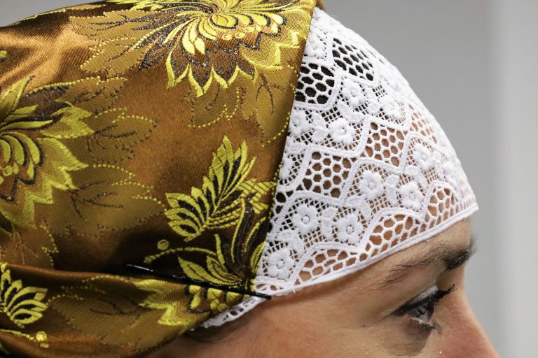 na zdjęciu głowa kobiety w tradycyjnym czepcu cieszyńskim