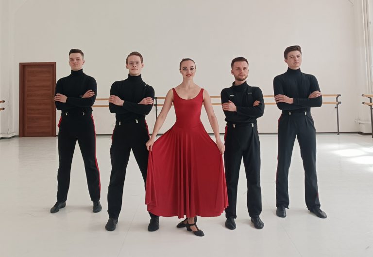 na zdjęciu stojąca tancerka i czterech tancerzy ubranych w stroje wizytowe