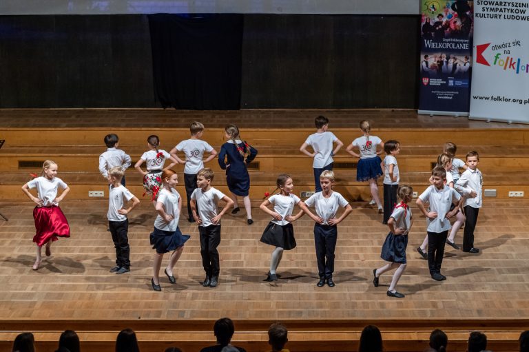 Na zdjęciu grupa dzieci tańczy na scenie.