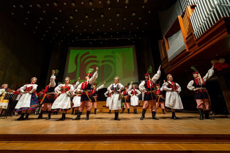Na zdjęciu grupa dzieci w strach krakowskich. Tańczą na scenie.