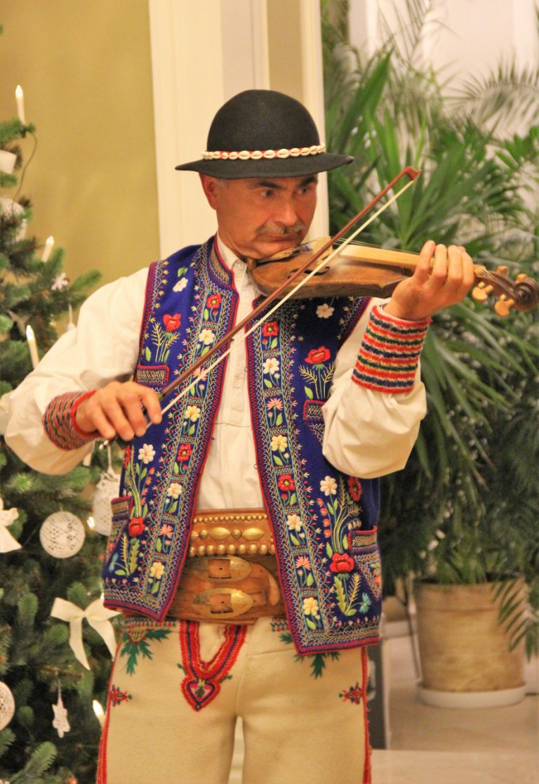 Mężczyzna w stroju góralskim gra na skrzypcach.