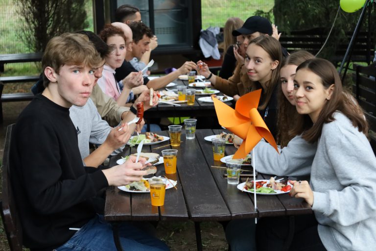 na zdjęciu grupa młodzieży jedząca posiłek