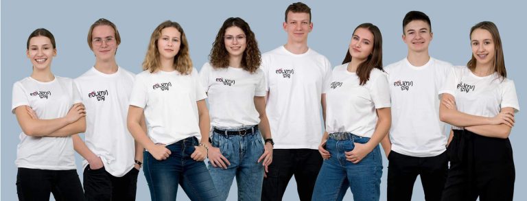 Grupa uśmiechniętych młodych ludzi w koszulakch z napisem 