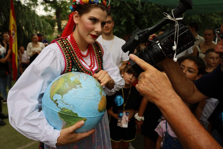 na zdjęciu dziewczyna w stroju regionalnym z globusem w rękach