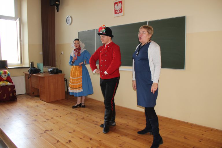Na zdjęciu para tancerzy w strojach z Dąbrówki Wielkopolskiej. Obok stoi kobieta- prelegent mówi.