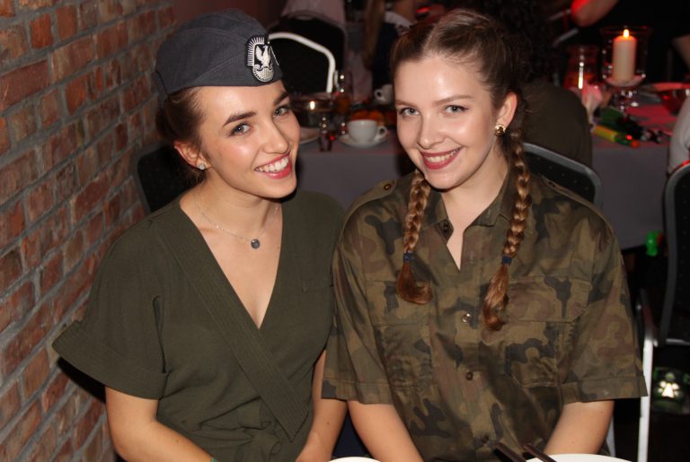 Na zdjęciu dwie kobiety w strojach wojskowych. Uśmiechają się do zdjęcia.