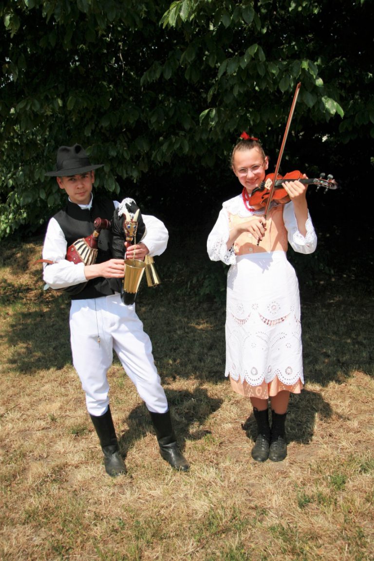 na zdjęciu dziewczyna i chłopak grający na dudach wielkopolskich i skrzypcach podwiązanych