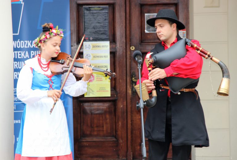 na zdjęciu dziewczyna grająca na skrzypcach i chłopak grający na dudach wielkopolskich