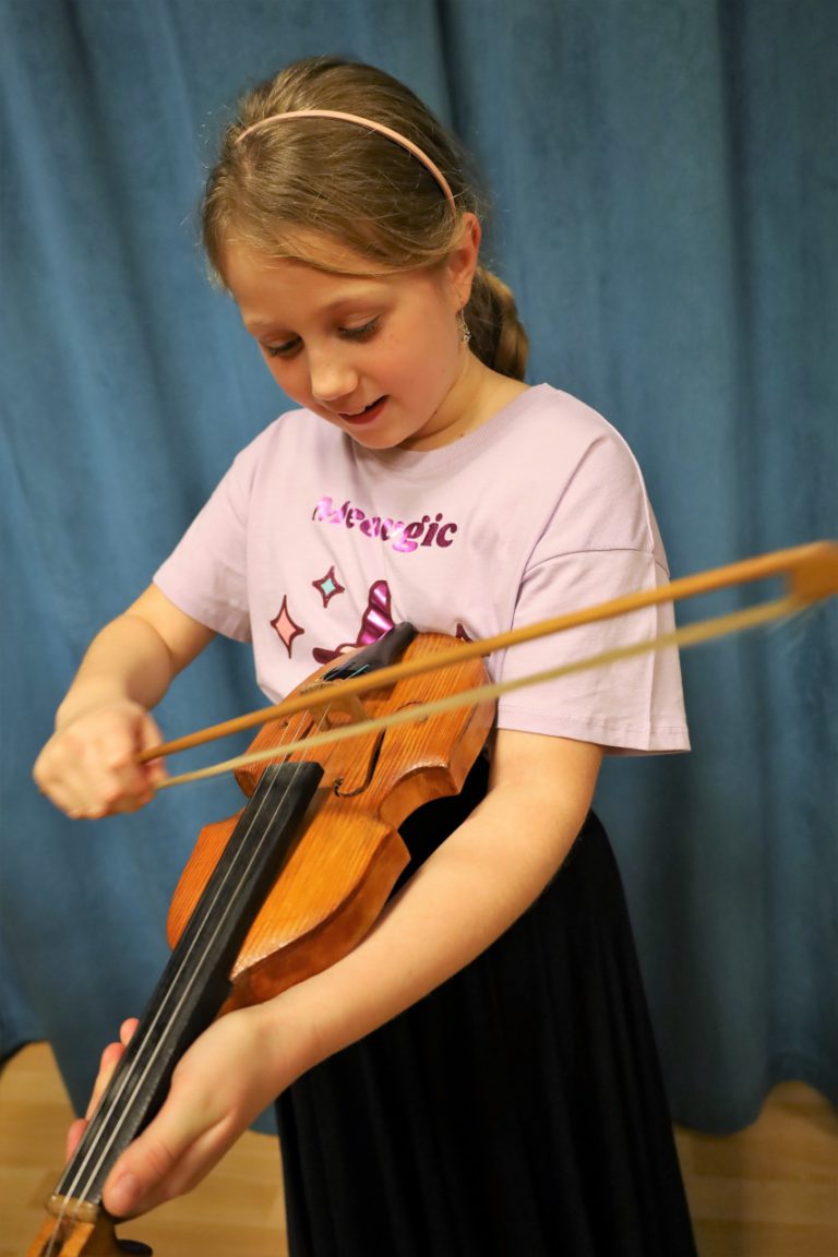 na zdjęciu dziecko grające na wielkopolskim instrumencie tradycyjnym