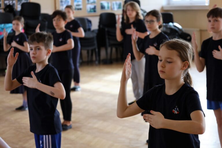 Dzieci ćwiczące taniec na sali gimnastycznej.